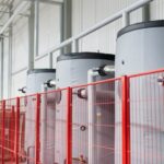 Zbiorniki izolowane na hali produkcyjnej z rurami i siatką ochronną